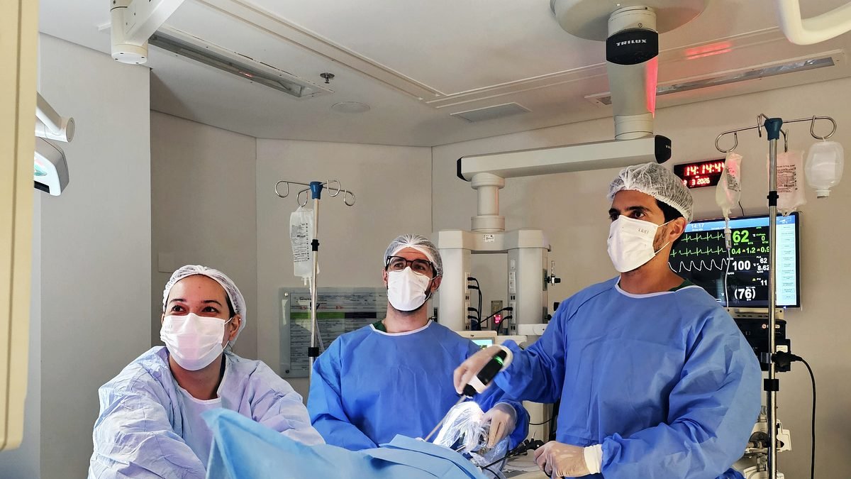 Equipe cirúrgica do Instituto em sala, com monitorização anestésica ao fundo